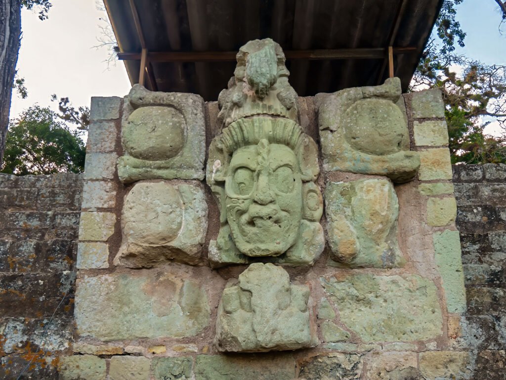 Close-up of a stone temple with a carved mask at the Copán UNESCO archaeological site, featured on a Copán day tour from Guatemala City by air — ideal for travelers who fly from Guatemala to Copán for a cultural experience.
