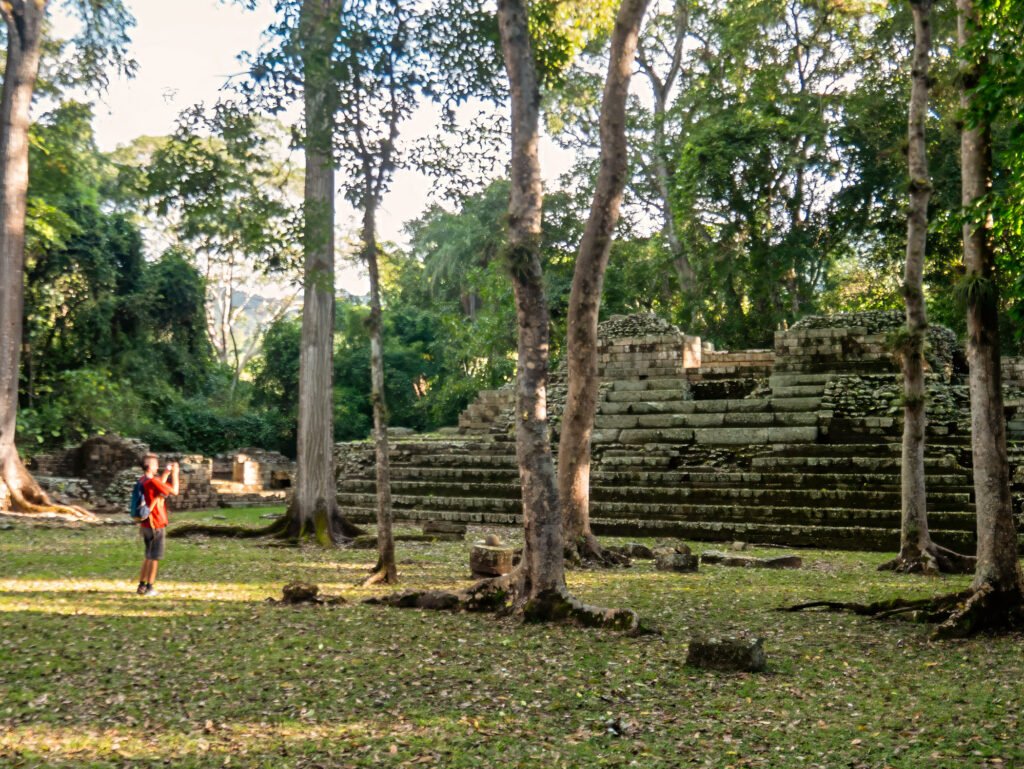 Traveler taking photos of a Maya pyramid inside the palace complex at the Copán UNESCO archaeological site, during a Copán day tour from Guatemala City by air — a unique experience for those who fly from Guatemala to Copán.