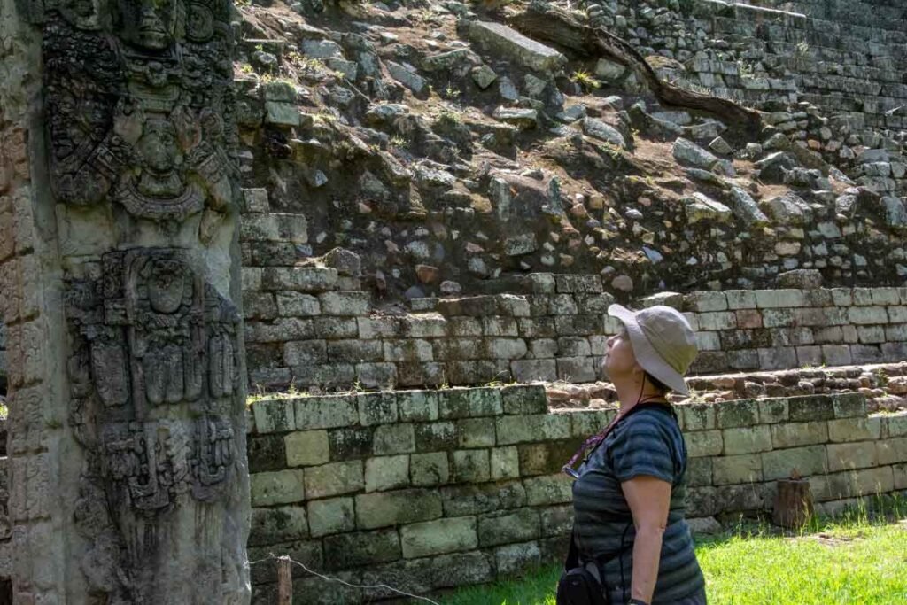 Woman admiring a detailed Maya stele at the Copán UNESCO archaeological site during a Copán day tour from Guatemala City by air.
